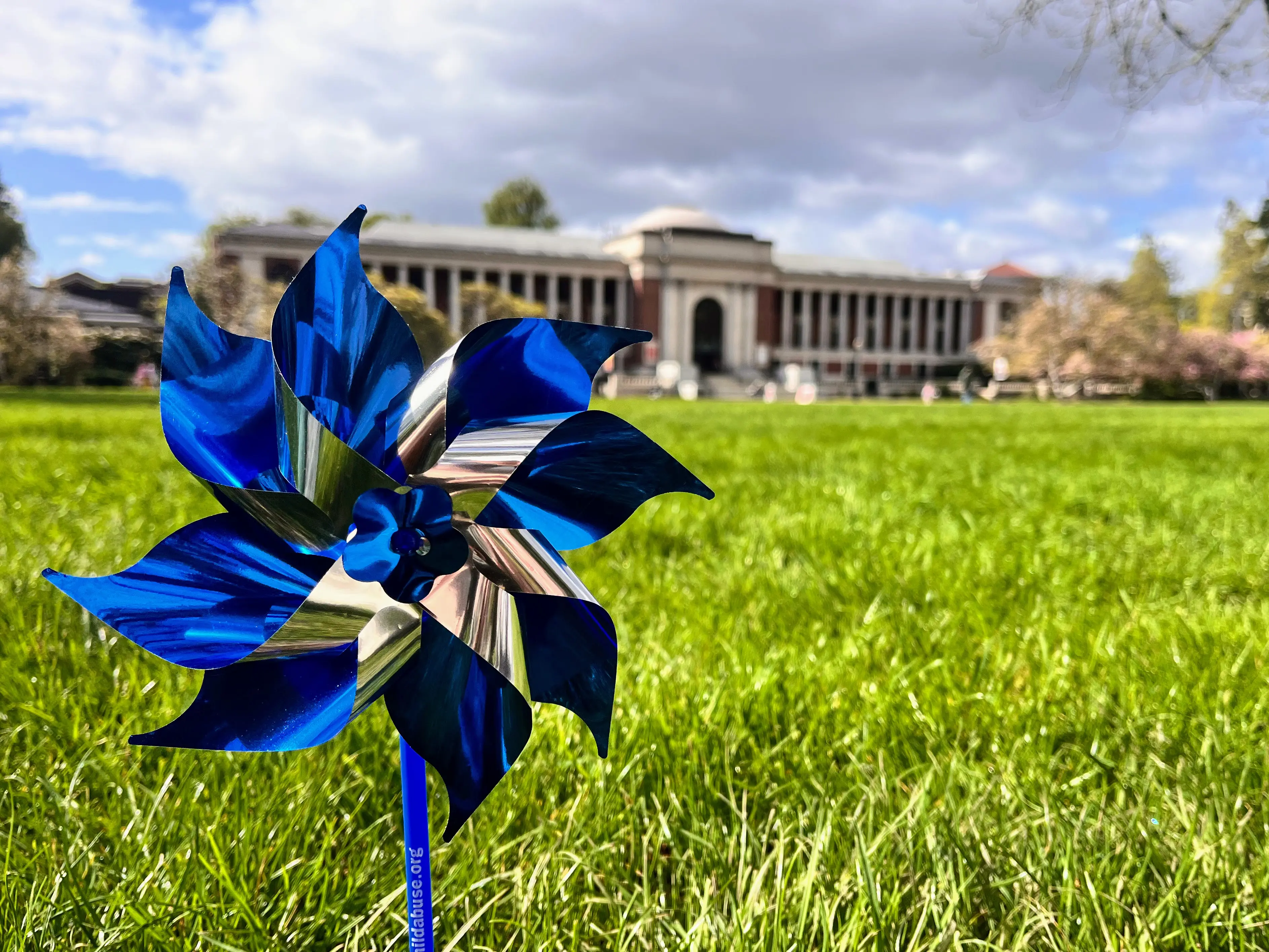 A blue and silver pinwheel on the grass in front of the OSU Memorial Union